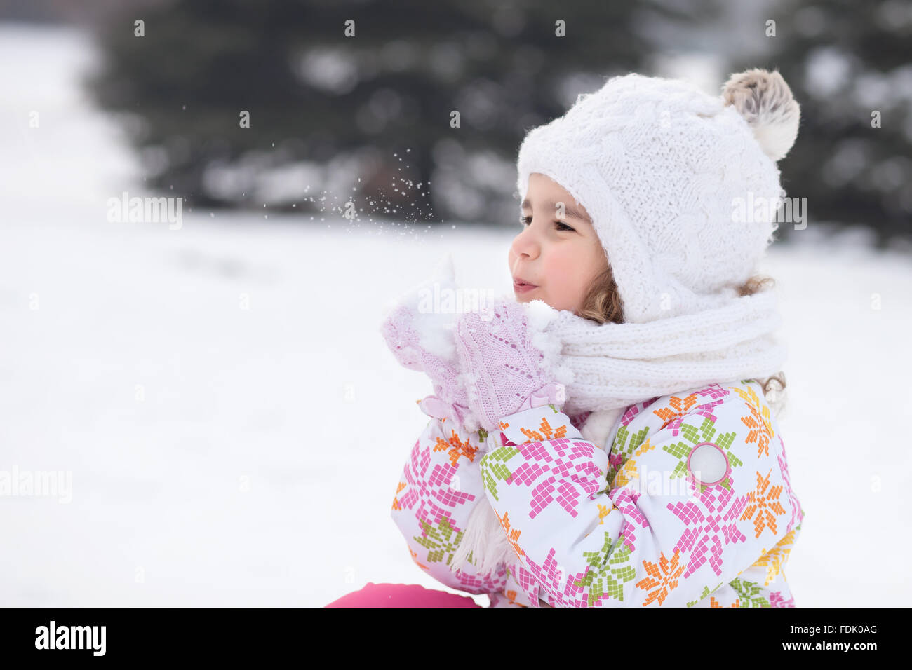 Mädchen bläst Handvoll Schnee Stockfoto