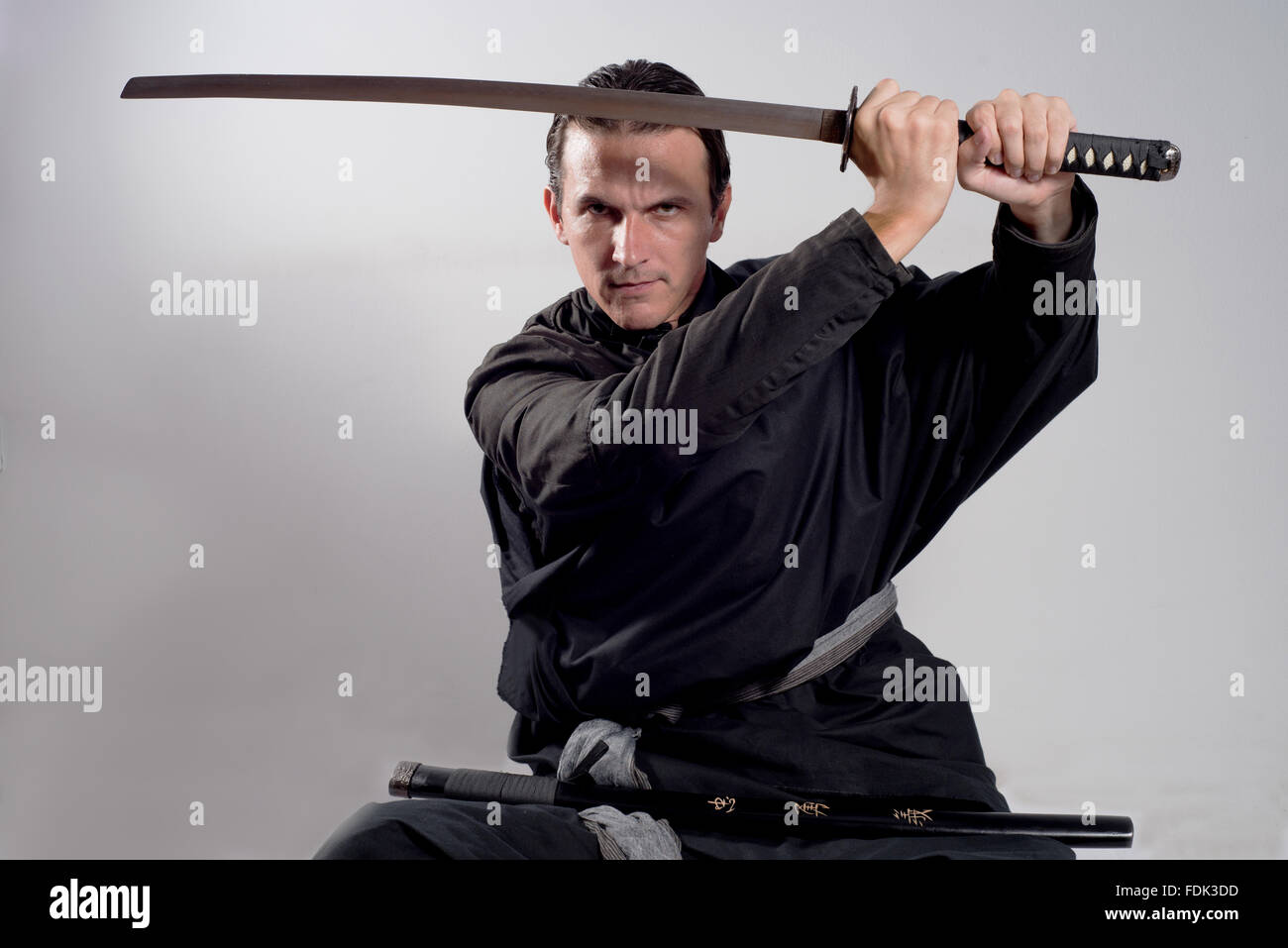 Mann, gekleidet wie ein Samurai Katana in der Luft halten Stockfoto