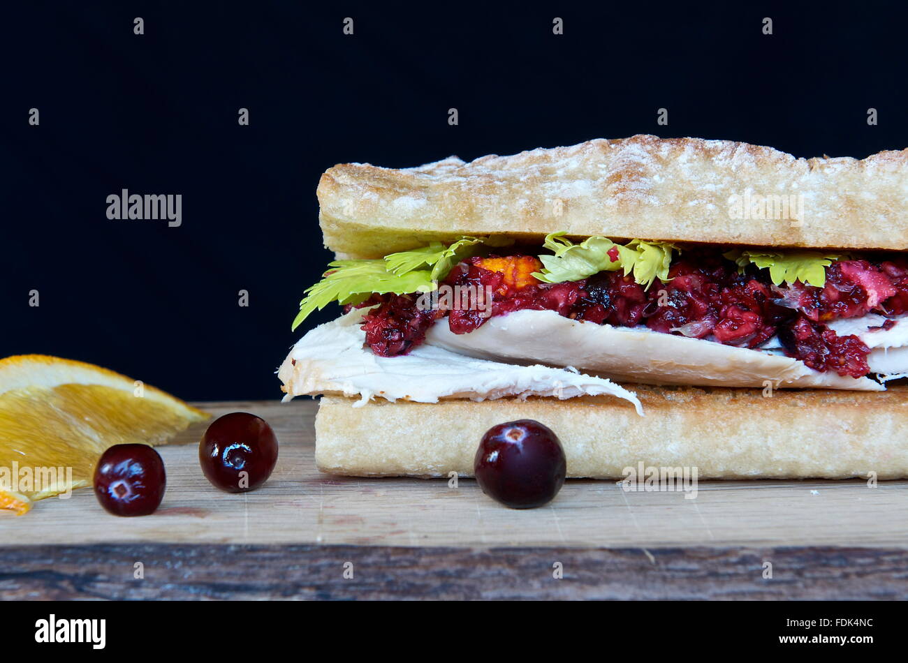 Gebratenes Huhn, Preiselbeere und Orange schmecken Baguette-Sandwich mit Garnierung Stockfoto