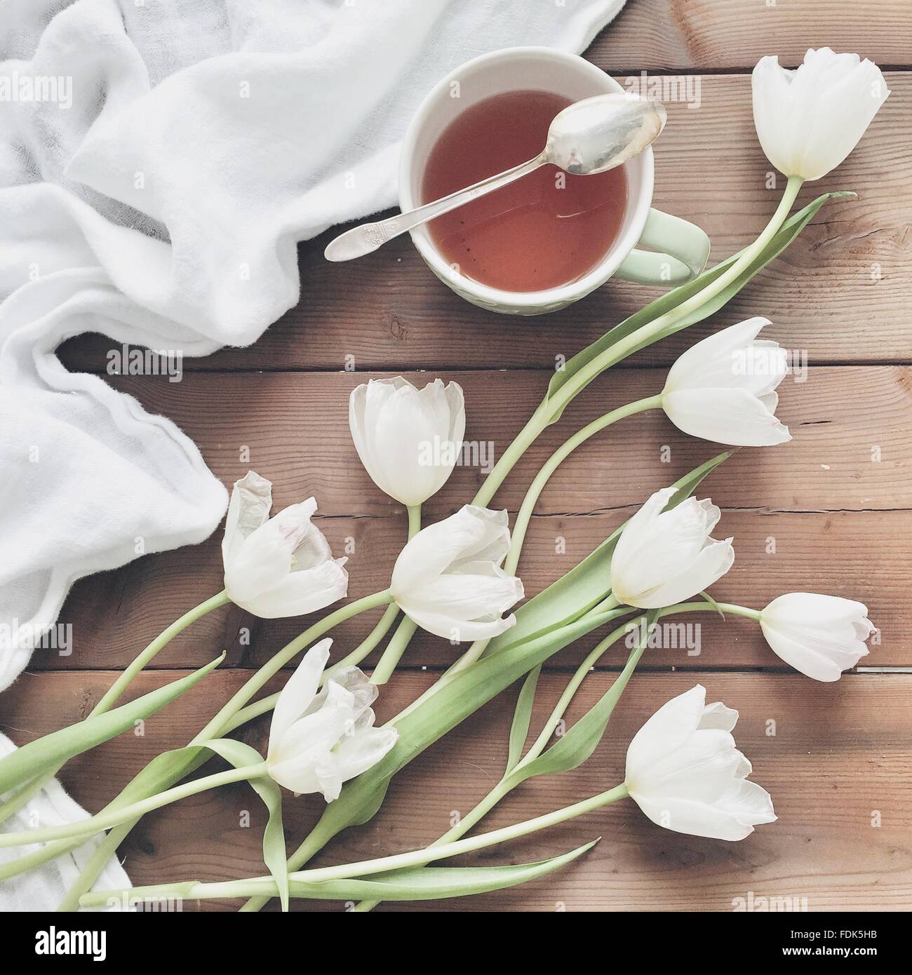 Weiße Tulpen auf einem Tisch neben einer Tasse Tee Stockfoto
