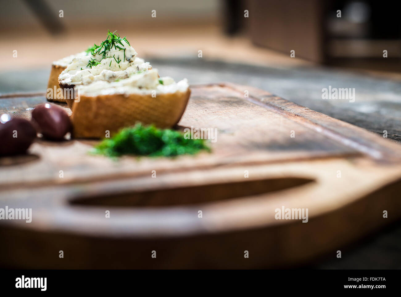 Bruschetta mit weicher Frischkäse und Oliven auf Schneidebrett Stockfoto