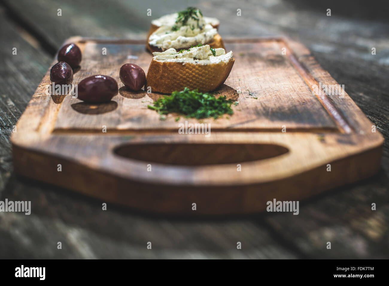 Bruschetta mit weicher Frischkäse und Oliven auf Schneidebrett Stockfoto