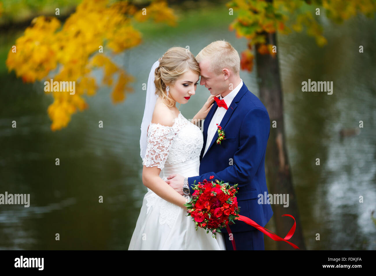 Hochzeitspaar umarmt am See im Herbst Stockfoto