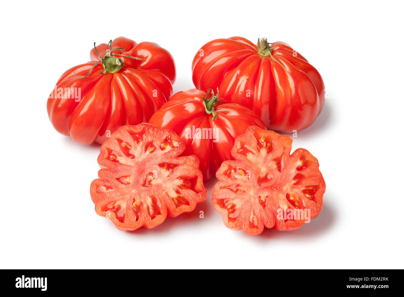 Frische ganze und halbe Bio Rebellion-Tomaten auf weißem Hintergrund Stockfoto