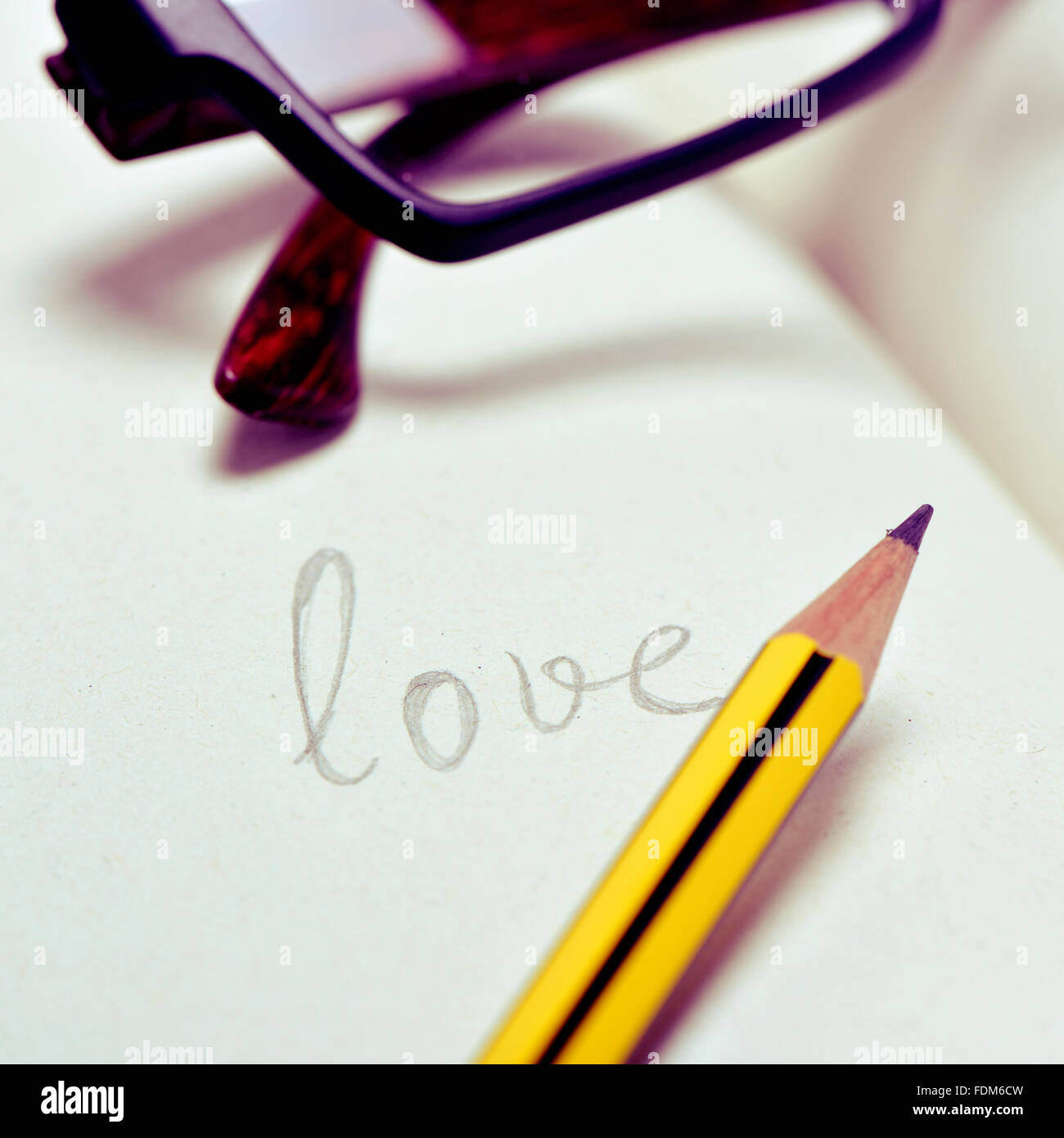 Nahaufnahme von ein paar Brillen und das Wort Liebe in einem Notizbuch mit Bleistift handschriftlich Stockfoto