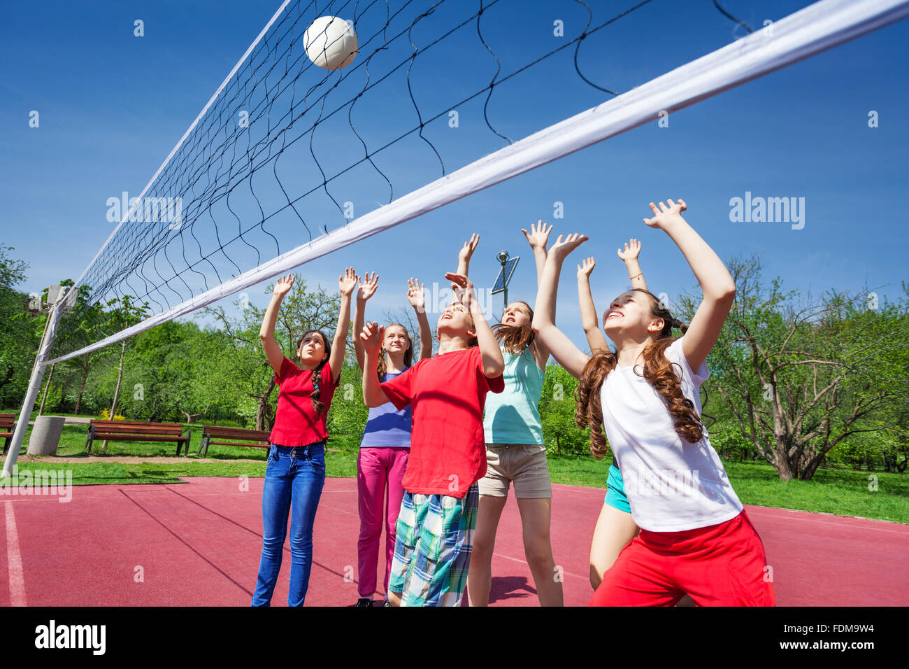 Gruppe von Jugendlichen mit Arme nach oben Volleyball spielen Stockfoto