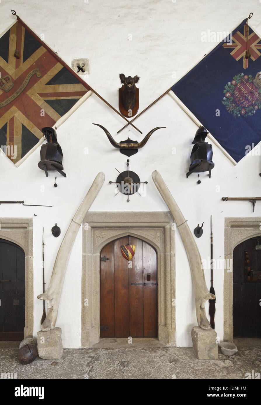 Ein Wal Kieferknochen Flanke das Tor zum Osten Wand in der Halle am Cotehele, Cornwall. Die beiden großen Farben gehören zu den 4. (Royal South Middlesex) Miliz, die von einem Mitglied der Familie Edgcumbe während der napoleonischen Kriege befohlen wurde. Stockfoto