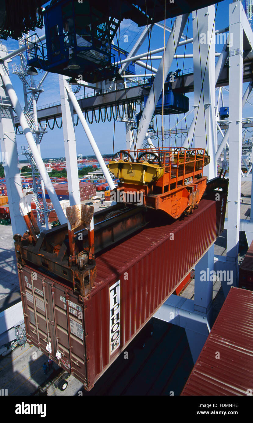 Import containerisierte Fracht wird von einem Container-Schiff und auf warten Sattelzüge an einem Hafen Dock abgeladen. Stockfoto