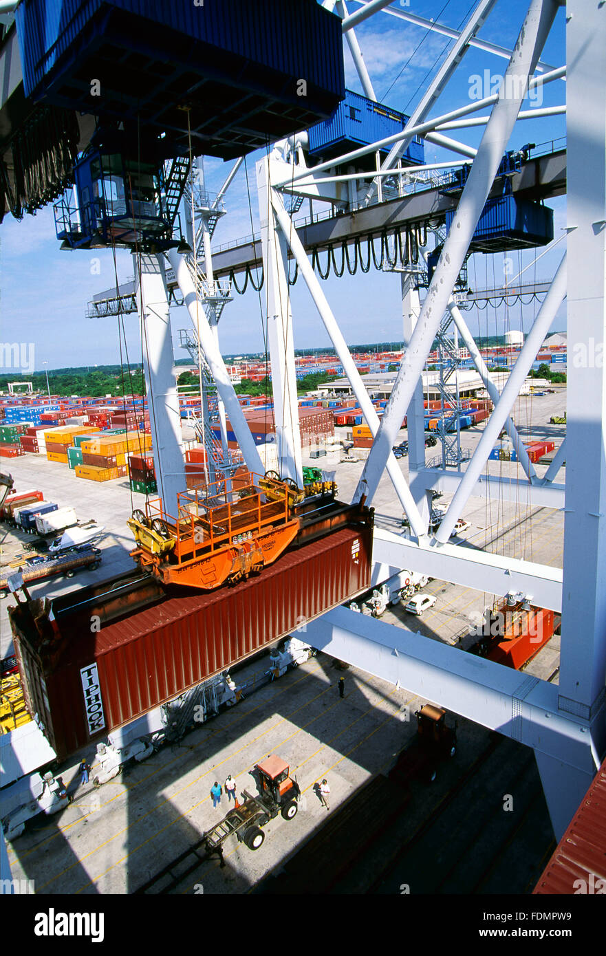 Import containerisierte Fracht wird von einem Container-Schiff und auf warten Sattelzüge an einem Hafen Dock abgeladen. Stockfoto