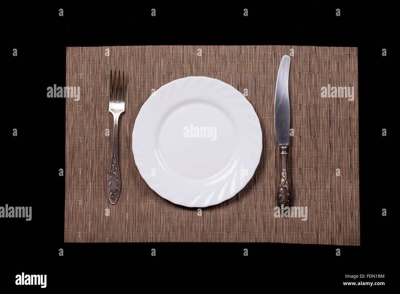 Teller, Löffel, Messer und Serviette auf schwarzem Hintergrund Ansicht von oben Stockfoto