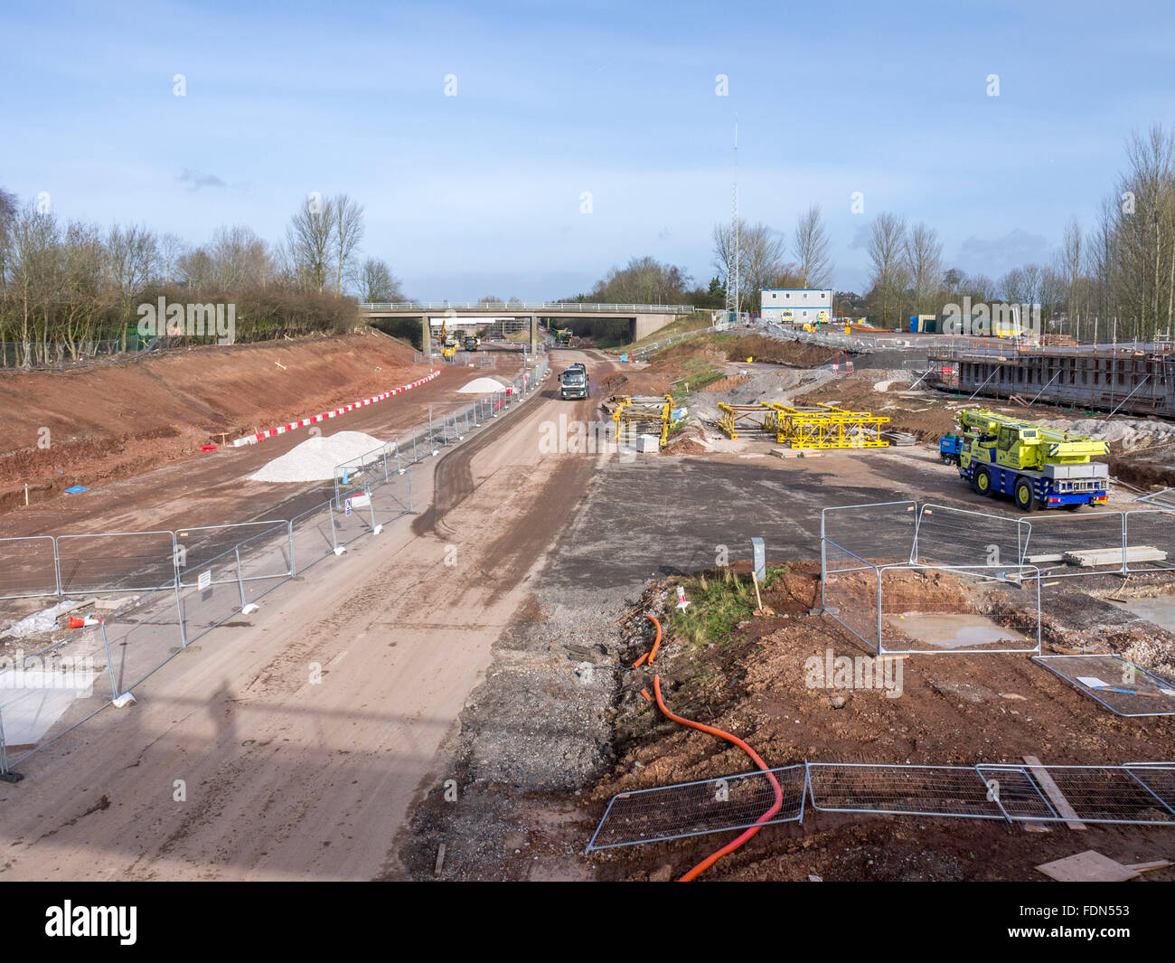 Straßenbau mit Zäunen, Pfeifen und eine Kehrmaschine in der Ferne. Stockfoto
