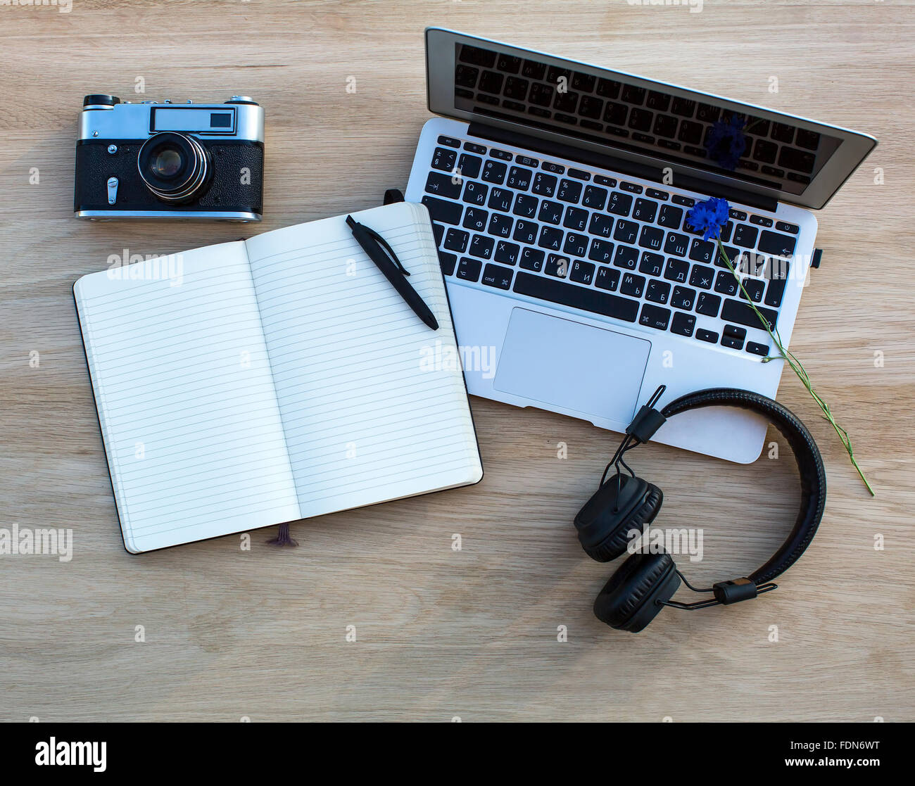 Laptop, Kamera, Kopfhörer und ein Notebook mit einem Stift auf einem  Holztisch gelegt Stockfotografie - Alamy
