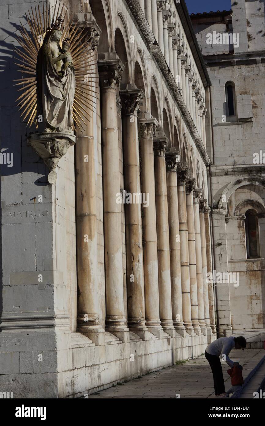 Eine Mutter spielt mit ihrem Sohn auf den Stufen unterhalb einer Kirche mit einer Madonna mit Kind auf der Suche nach unten Stockfoto