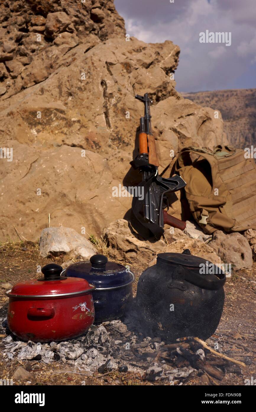 Tee und Essen Töpfe Heizung am offenen Feuer in den Bergen Kurdistans mit einer AK47 aufgestützt hinter. Stockfoto