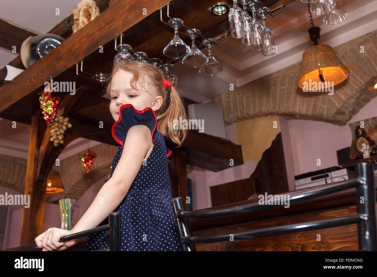 kleines Mädchen auf einem Stuhl in der bar Stockfoto