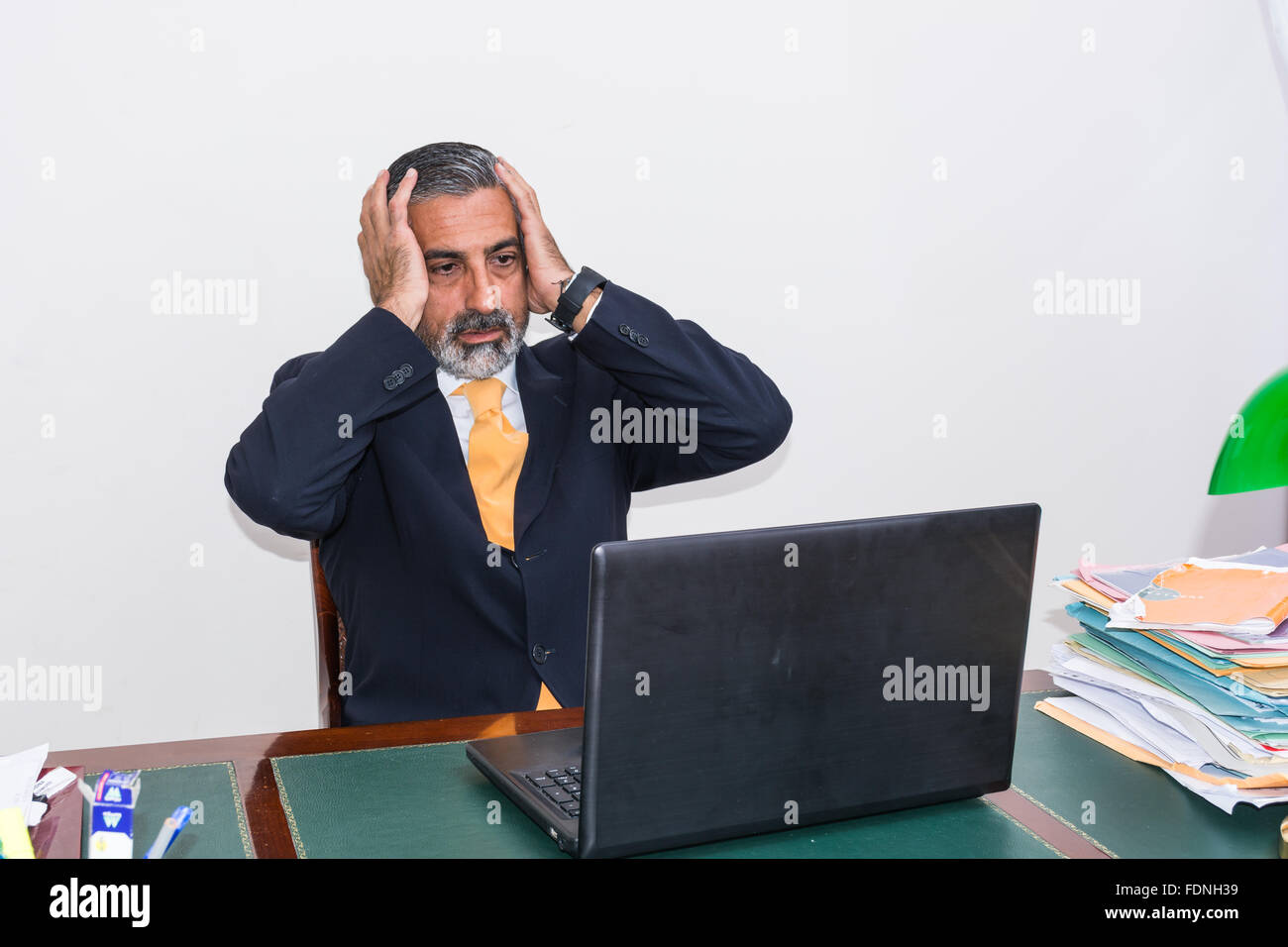 Verzweifelter Geschäftsmann. Allein in seinem Büro, vor dem Schreibtisch mit dem Computer, es Panik, Depression. Stockfoto