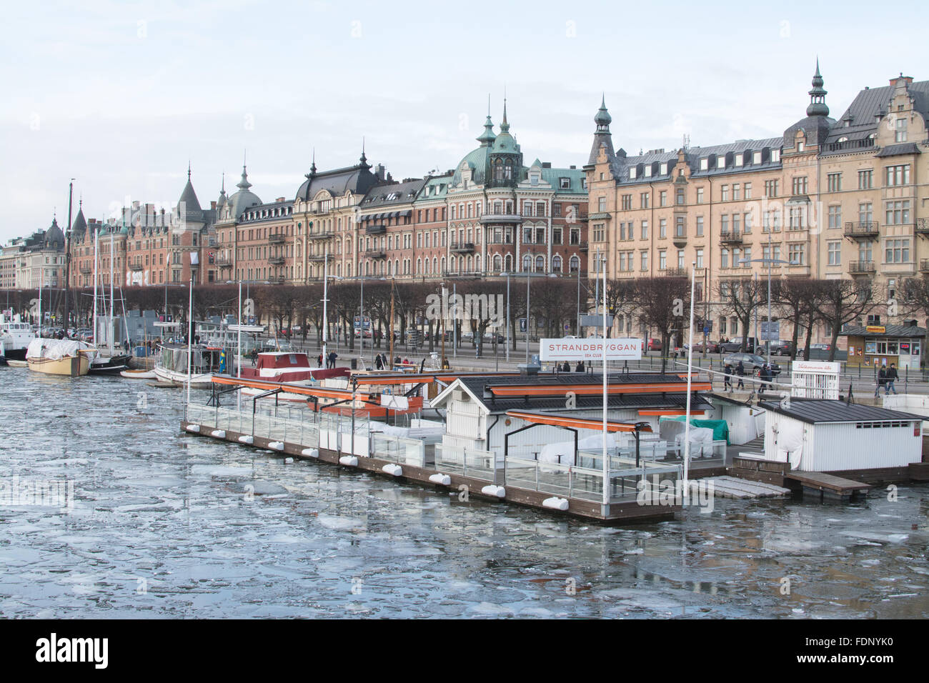 Stockholm, Schweden am Wasser im Winter - Strandbryggan Sea Club und Gebäude entlang Blickrichtung Stockfoto