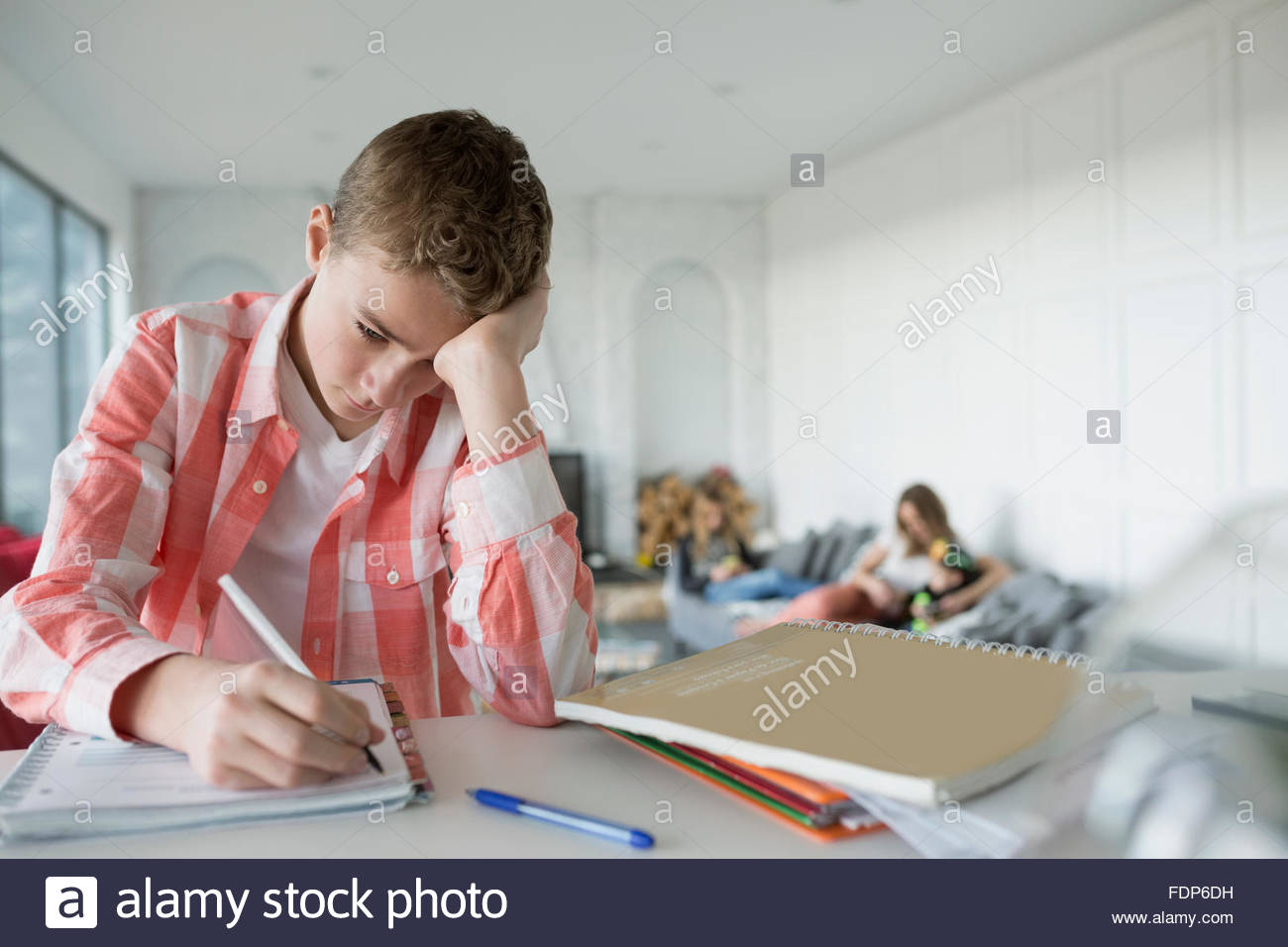Müde junge Hausaufgaben am Küchentisch Stockfoto