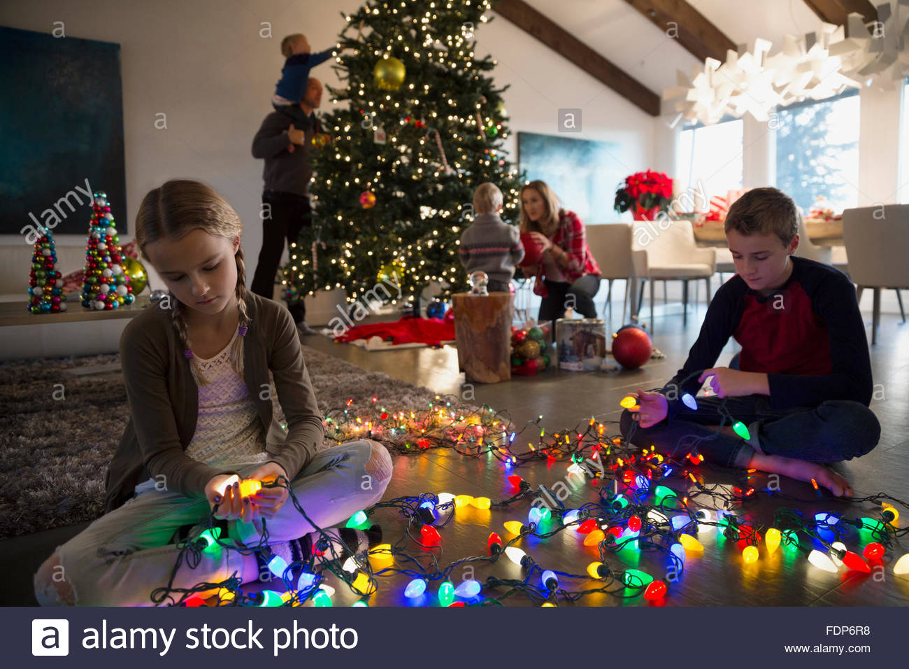 Bruder und Schwester entwirren Weihnachtsbaum Lichterkette Stockfoto