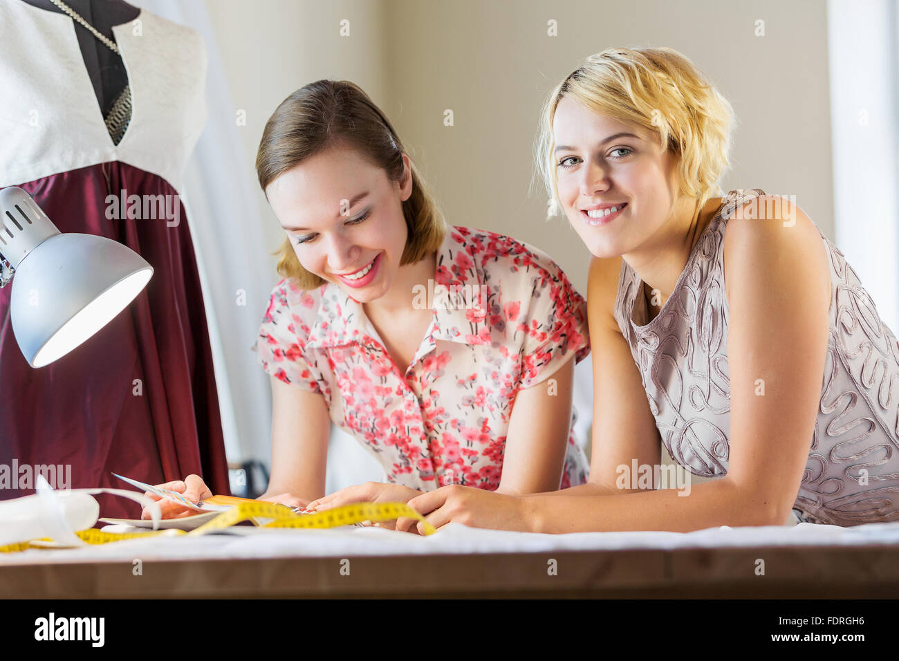 Zwei attraktive Frauen an Schneiderinnen Auswahl Designs Stockfoto