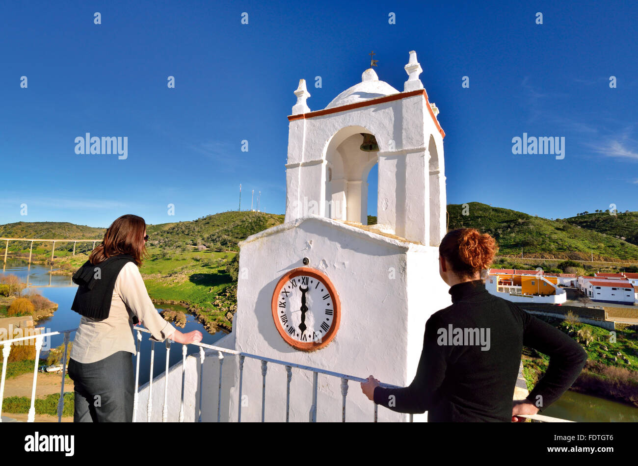 Portugal, Alentejo: Zwei Frauen, die Aussicht auf mittelalterliche Turm Torre de Relógio und Fluss Guadiana in Mértola Stockfoto