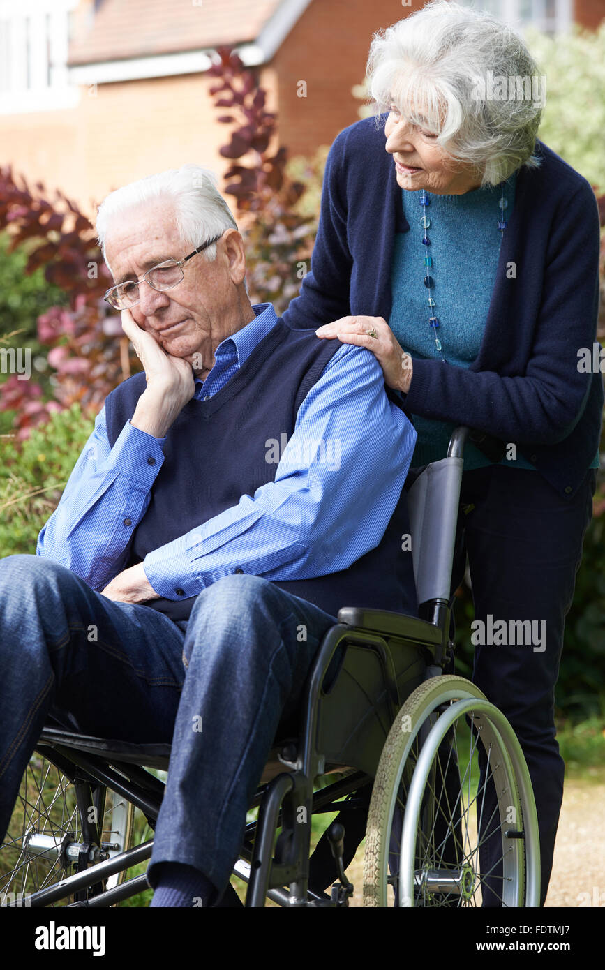 Deprimiert Senior Mann im Rollstuhl geschoben von Frau Stockfoto