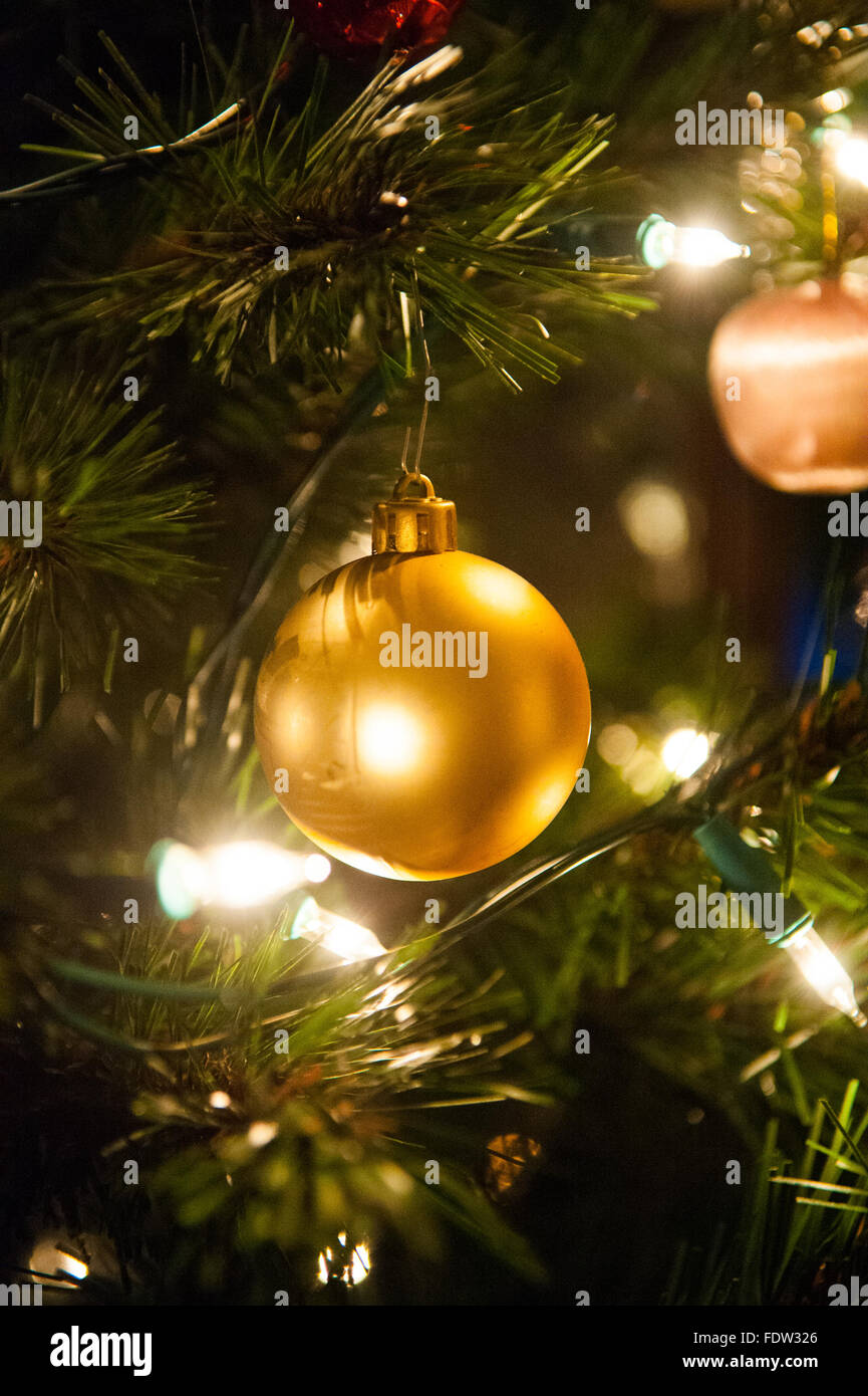 Goldene Kugel am Weihnachtsbaum mit Lichterketten beleuchtet. Stockfoto