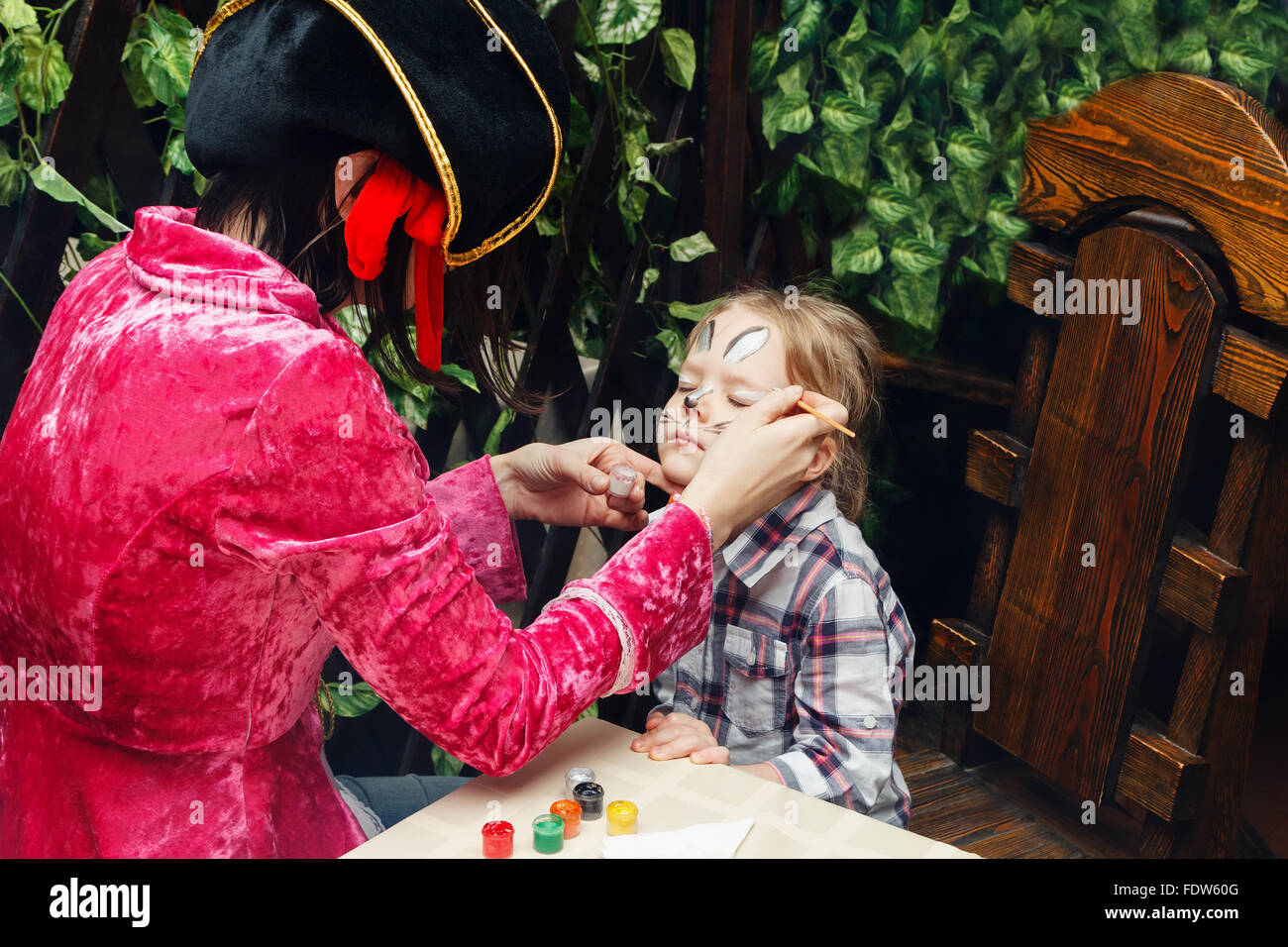 Frau malt das Gesicht eines Mädchens Stockfoto