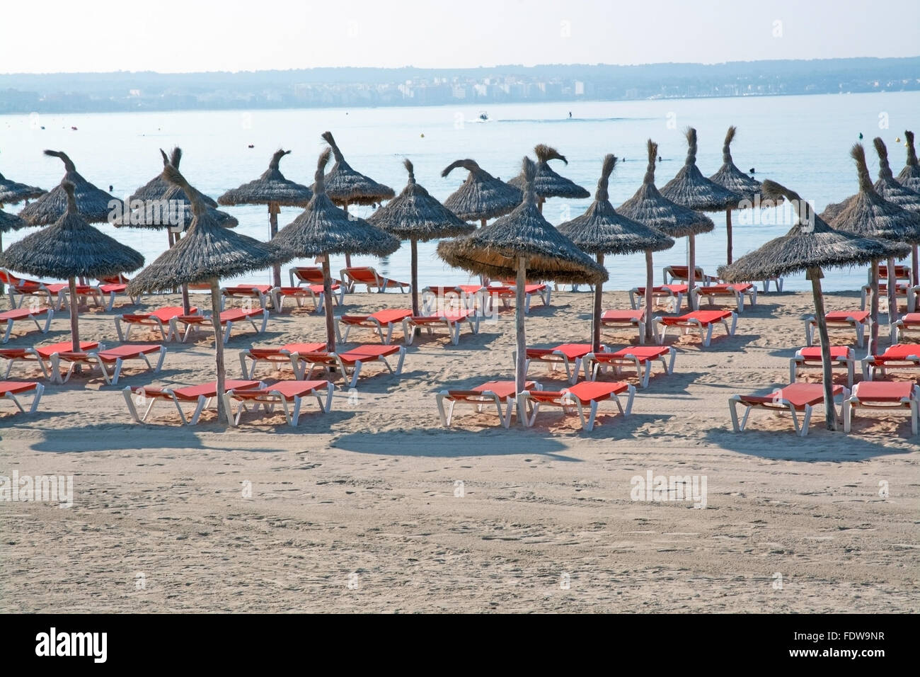 Sonnenschirme und Lounges auf Mallorca Sandstrand an einem sonnigen Sommermorgen im Juli Stockfoto