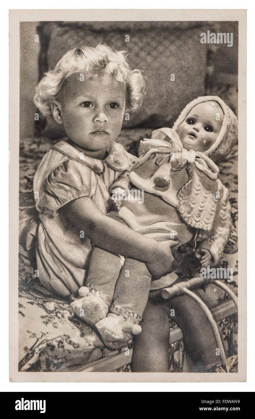 Kleines Mädchen mit einer großen Puppe spielt. Vintage Bild mit originalen Filmkorn und Unschärfe Stockfoto