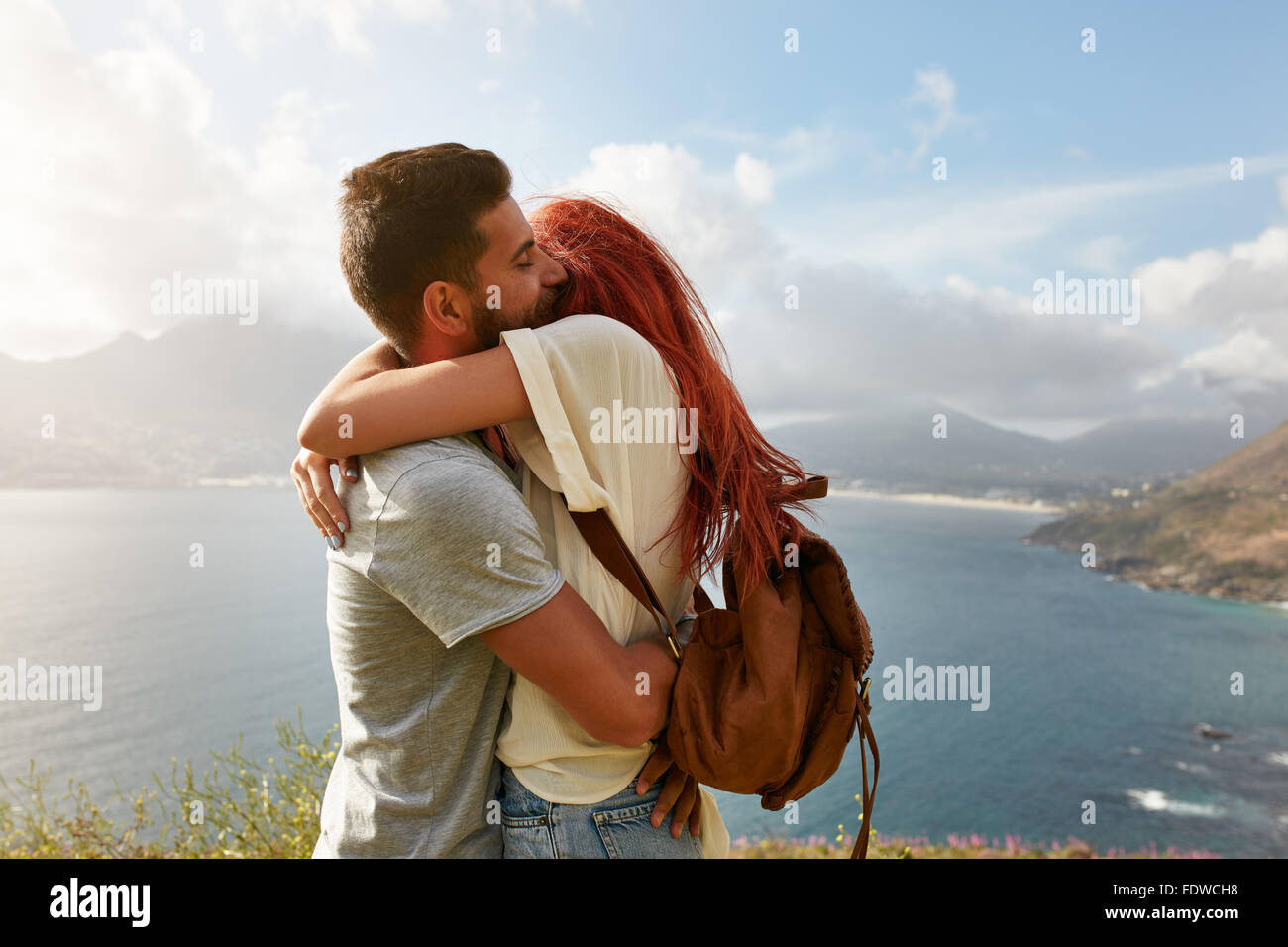 Portrait über ein glückliches junges Paar eine romantische Umarmung im Freien zu genießen. Junger Mann umarmt seine Freundin beim stehen auf einem Hügel Stockfoto