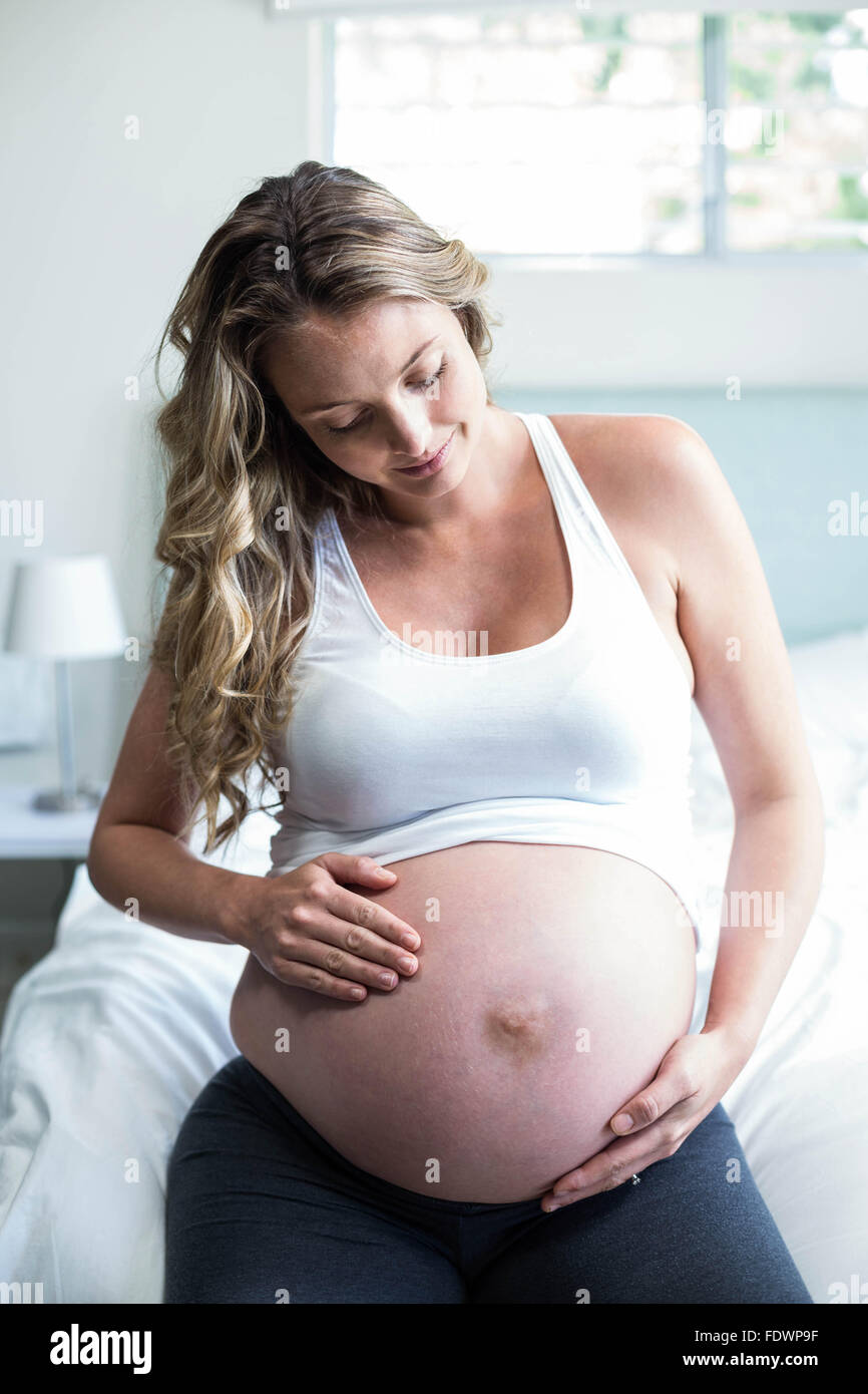 Schwangere Frau massieren ihren Bauch Stockfoto