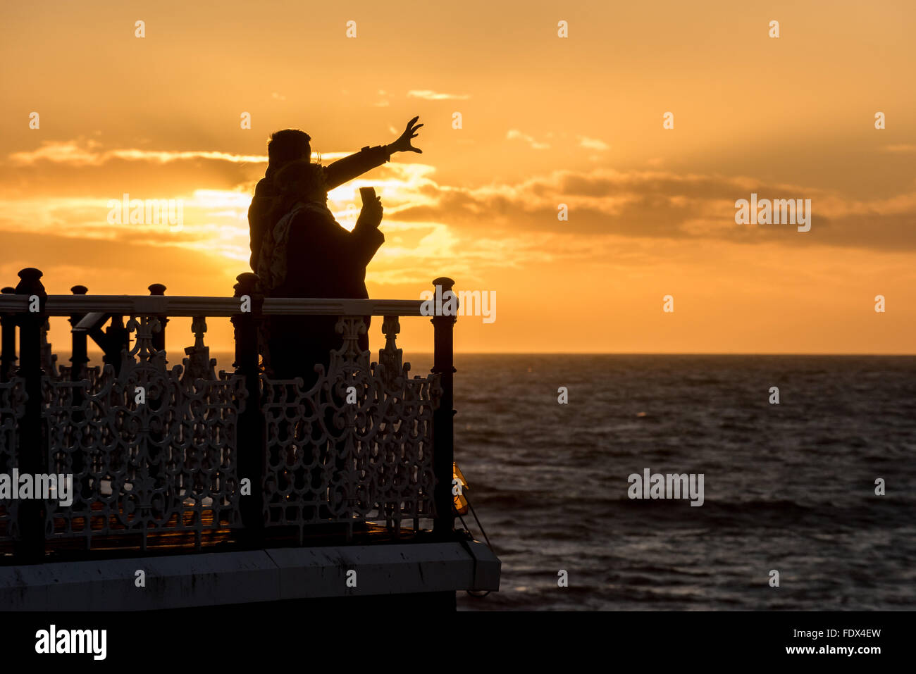 Zwei Menschen den Sonnenuntergang an Brightons Palace Pier. Stockfoto