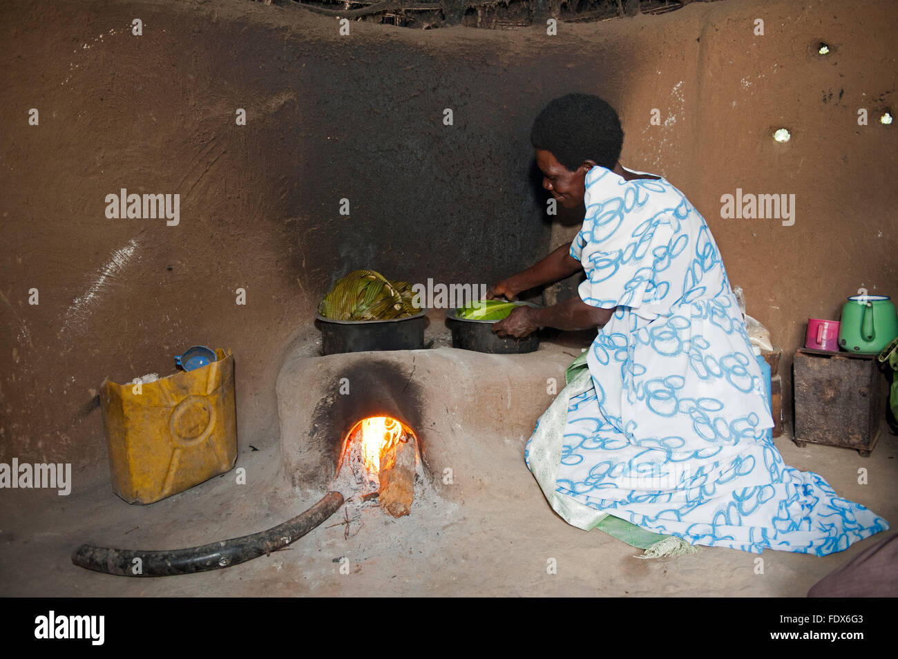 Ugandischen Dame Zubereitung einer Mahlzeit in einer Pfanne mit Mais und Banane Blätter auf ein Efficency Herd. Uganda. Stockfoto
