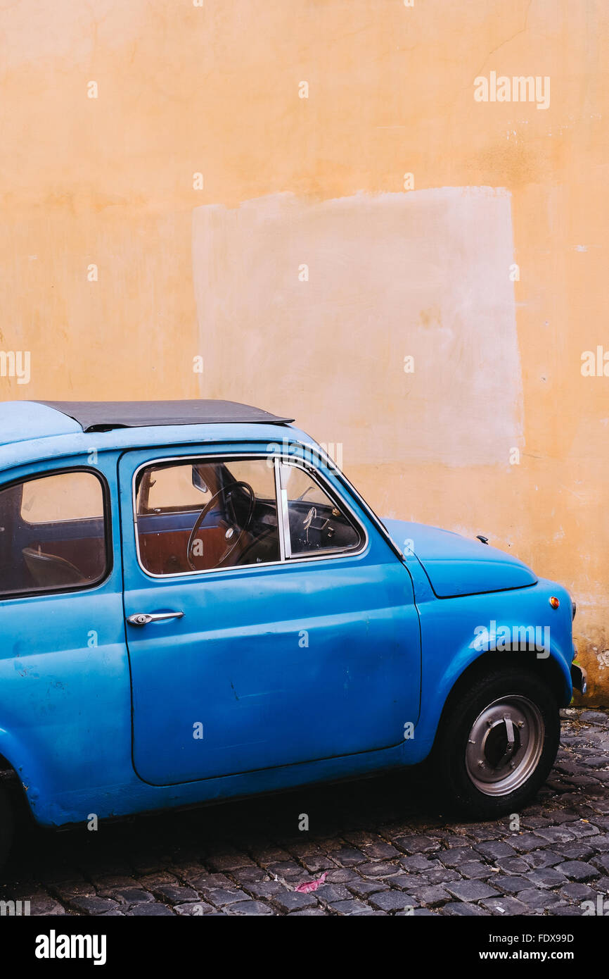 Ein helles Blau Vintage geparkten Fiat 500 gegen eine gelbe Wand in Rom, Italien Stockfoto