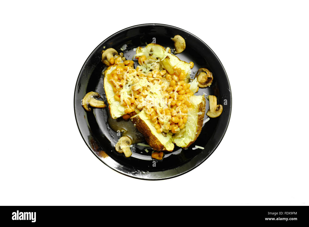 Eine Ofenkartoffel mit Bohnen, Pilzen und Käse auf einer schwarzen Platte vor weißem Hintergrund fotografiert Stockfoto