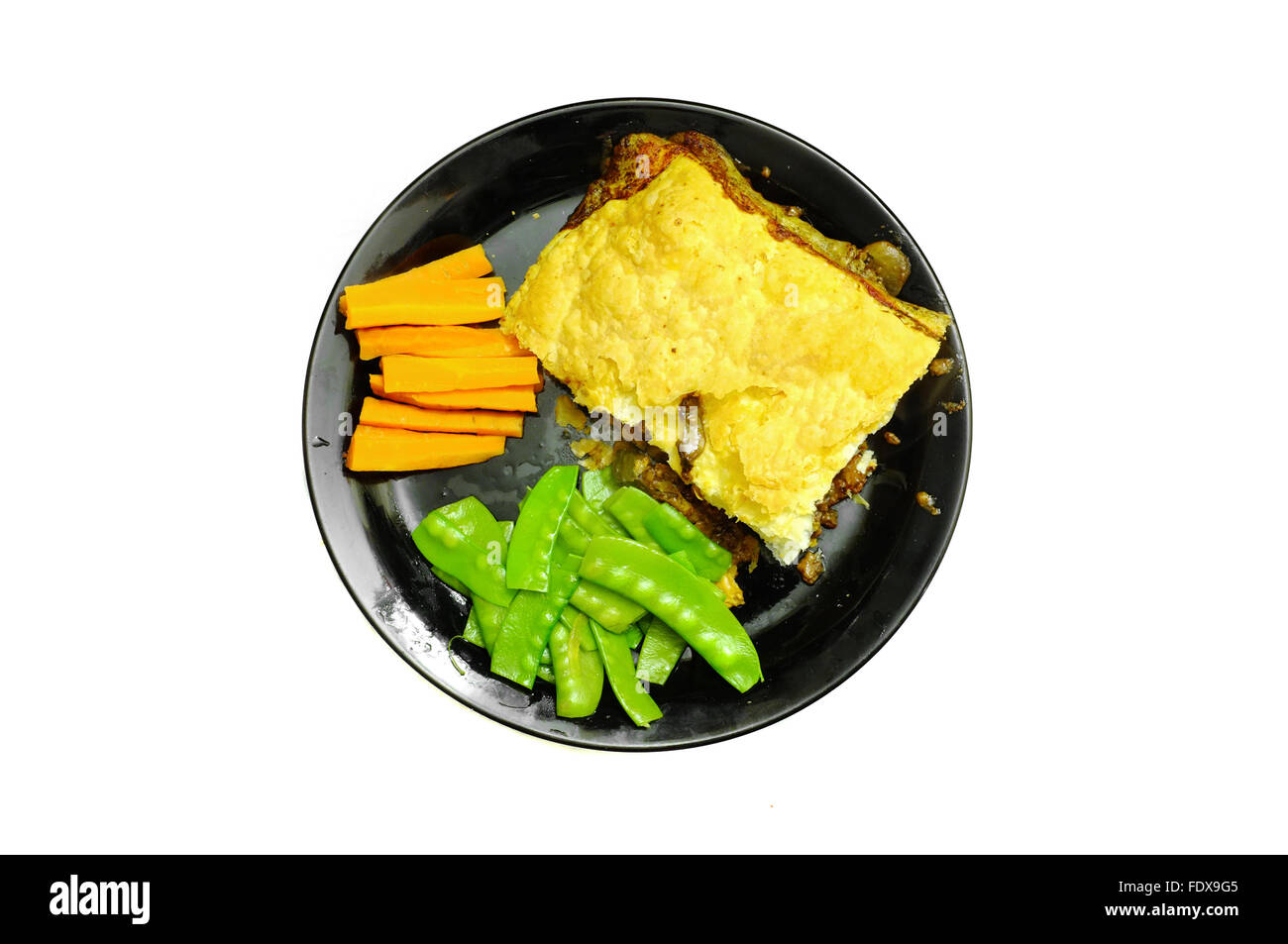 Ein Teller mit Kuchen und Gemüse auf einer schwarzen Platte vor weißem Hintergrund fotografiert Stockfoto