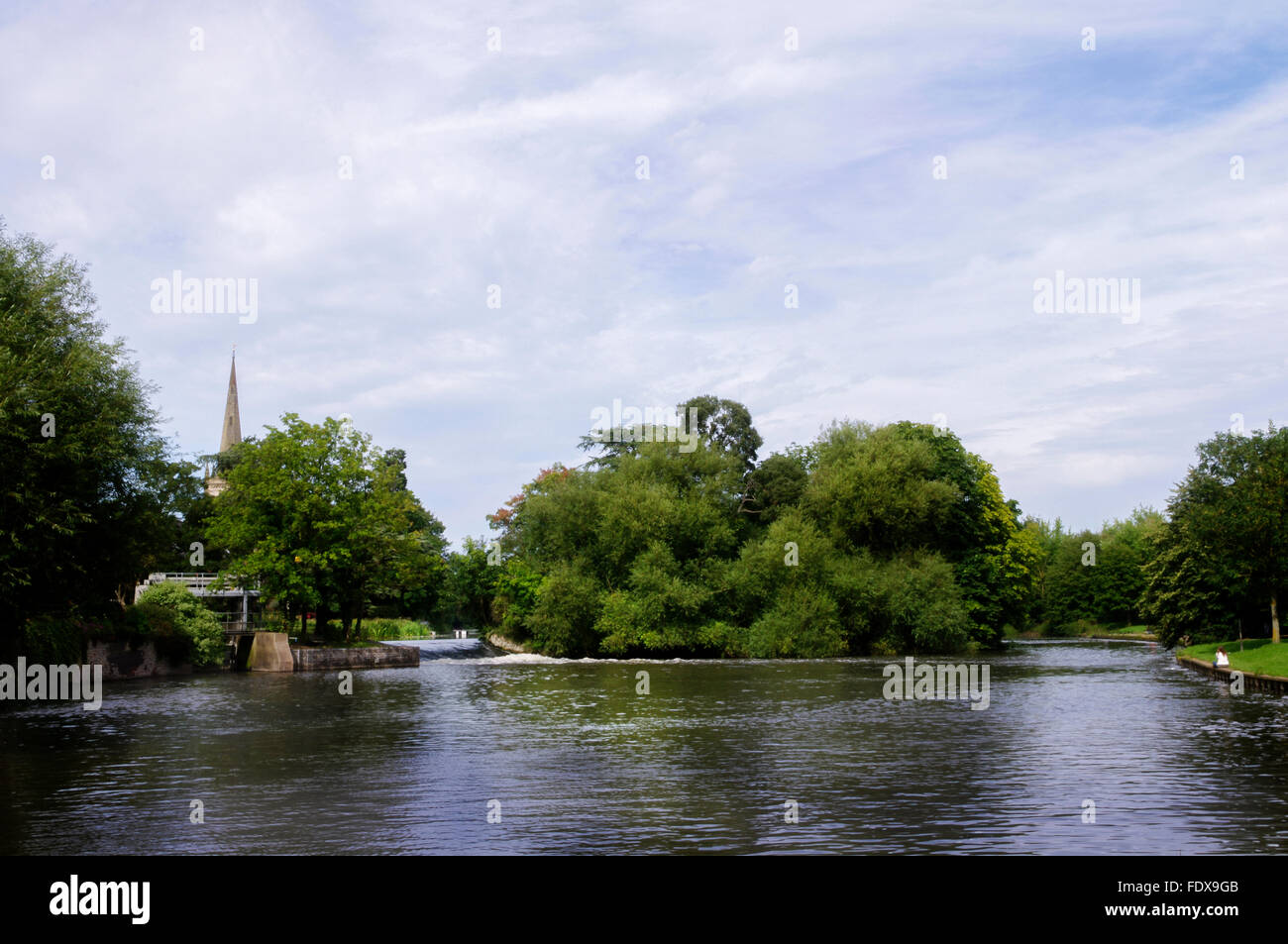 Blick über das Wasser des Flusses Avon zu Lucys Mühle Weir, Stratford-upon-Avon, mit dem Turm der Heiligen Dreifaltigkeit jenseits. Stockfoto