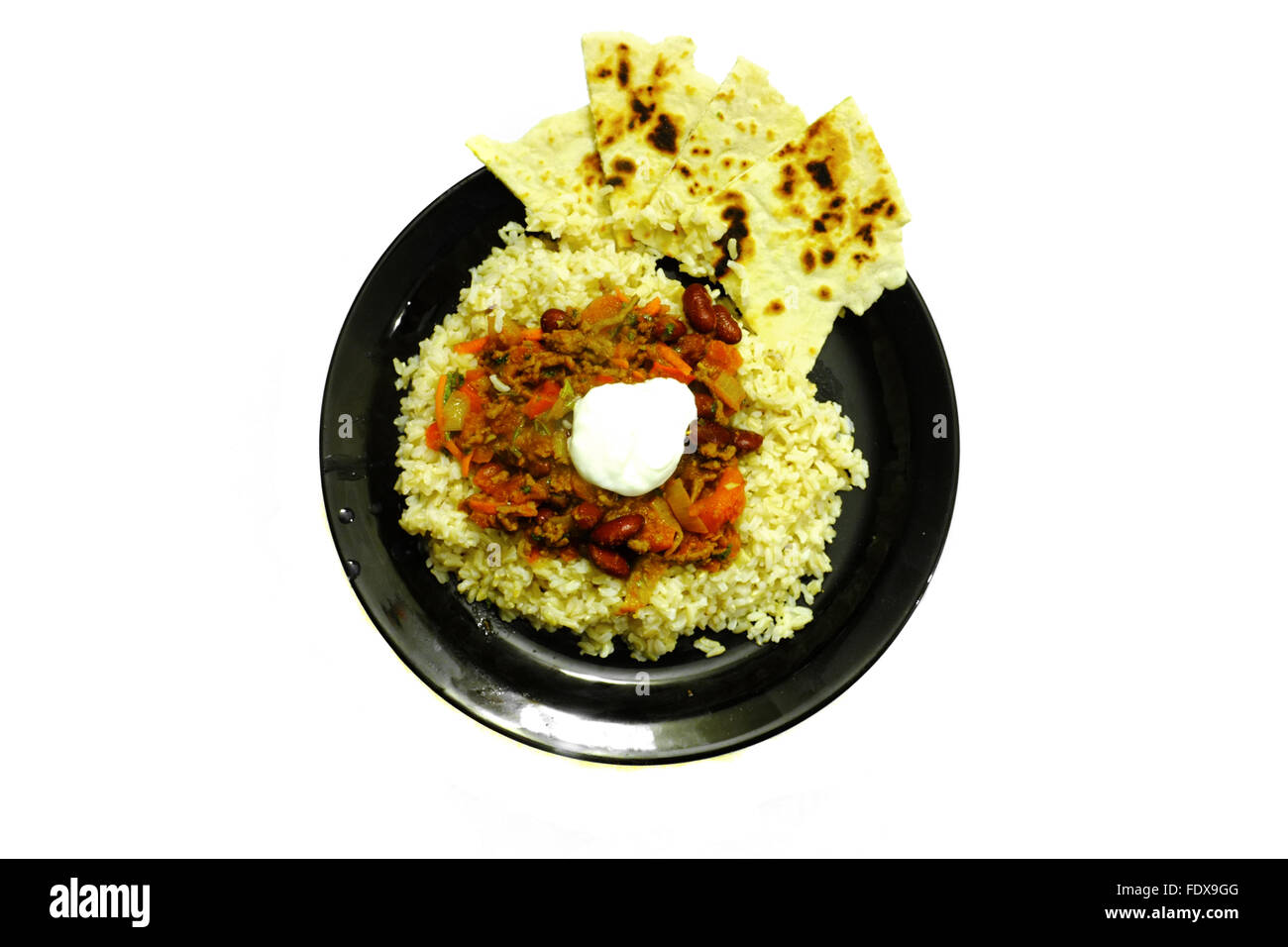 Ein Teller mit Chili Con Carne auf einer schwarzen Platte vor weißem Hintergrund fotografiert Stockfoto