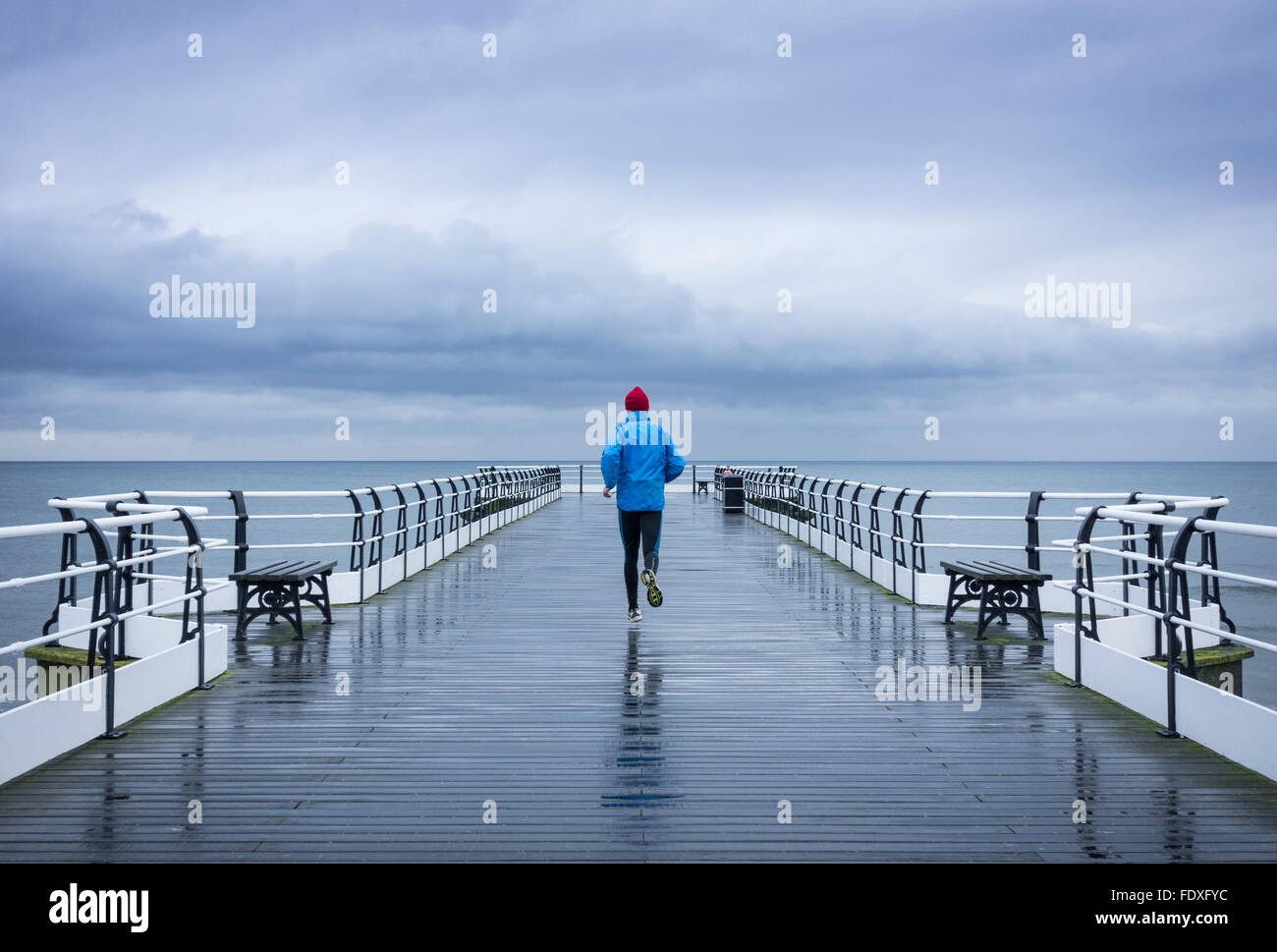 Reifer mann Jogging auf Saltburn Pier im Regen. Saltburn durch das Meer. North Yorkshire. Großbritannien Stockfoto