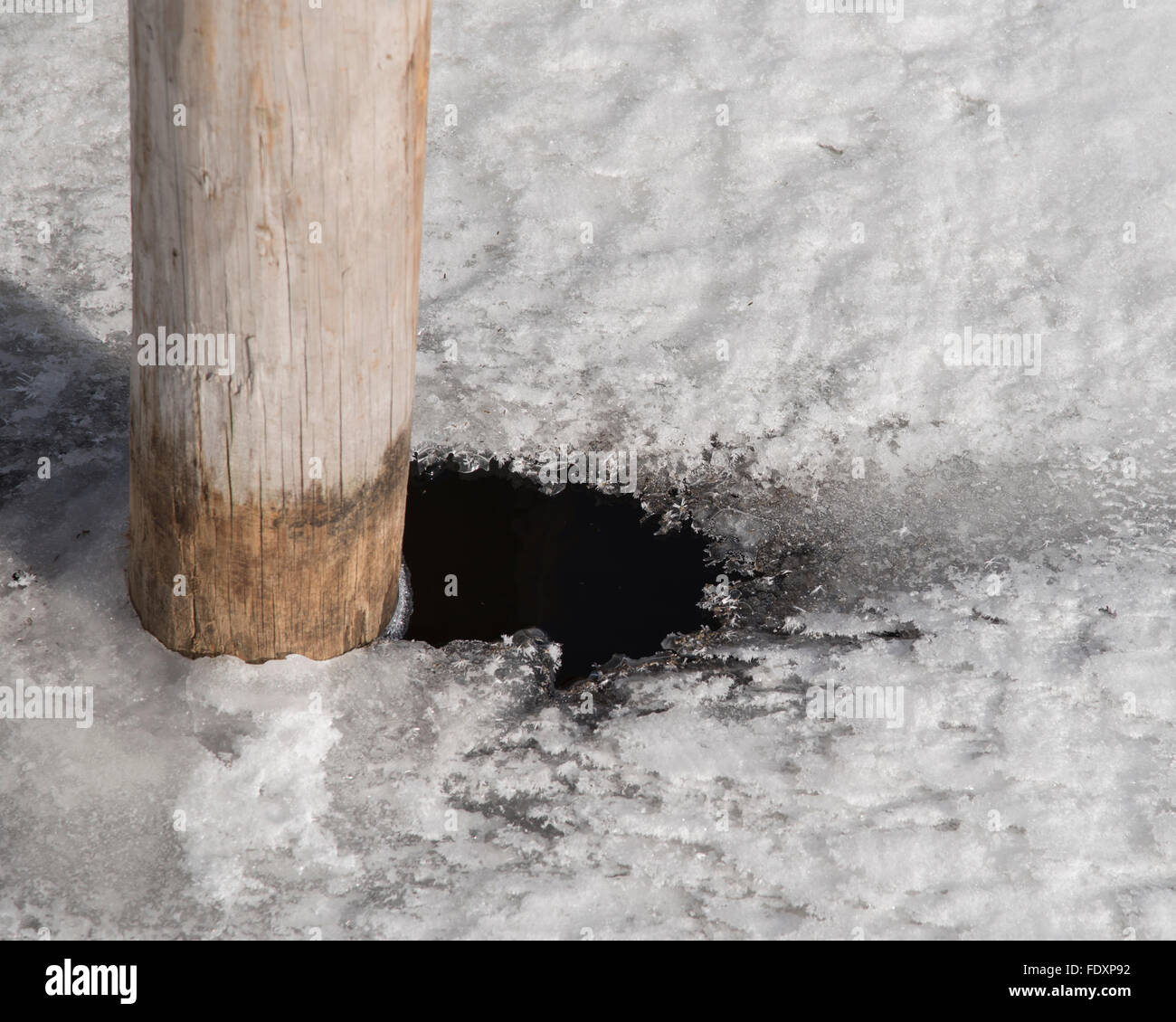 Schnee und Eis ist aufgetaut, um den Pfosten, so dass ein kleines Stück des Oberflächenwassers auf dem See. Stockfoto