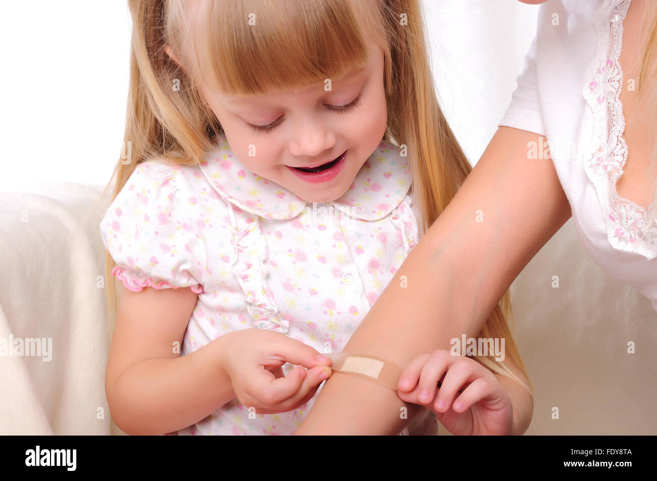 Das kleine Mädchen setzt ein Pflaster auf seiner Mutter die hand Stockfoto