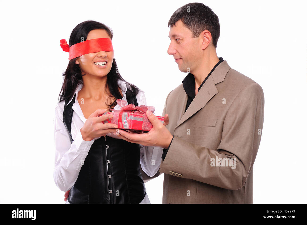 Der junge Mann gibt seine Freundin ein Geschenk. Das Mädchen rote Augenbinde Stockfoto