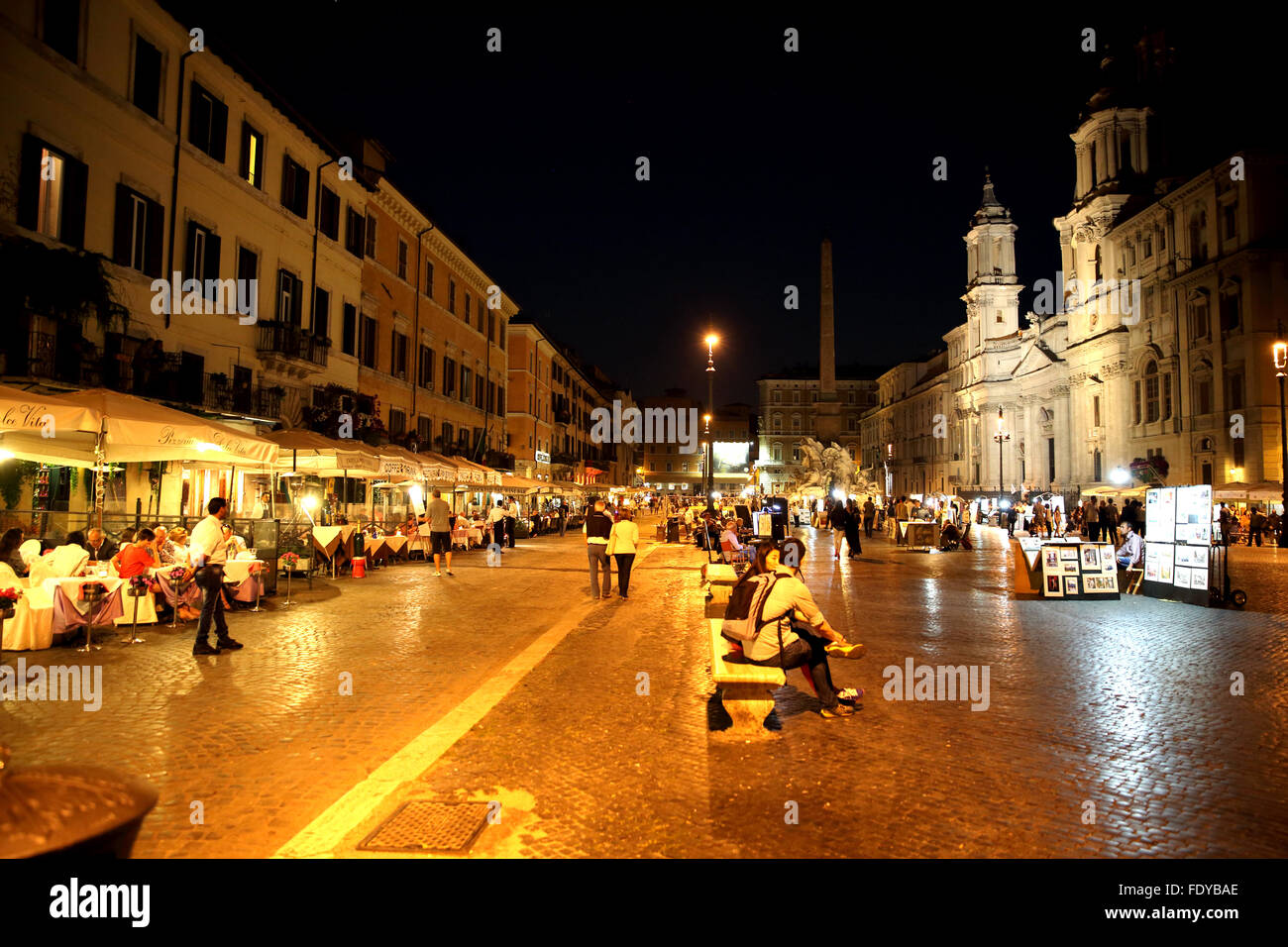 Restaurants und Künstler sind Teil der Attraktion der Piazza Navona in Rom bei Nacht. Stockfoto
