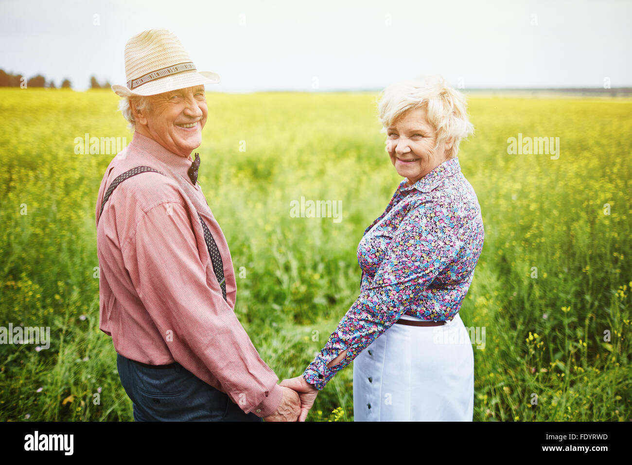 Liebevolle Senioren halten mit den Händen stehend auf Wiese Stockfoto