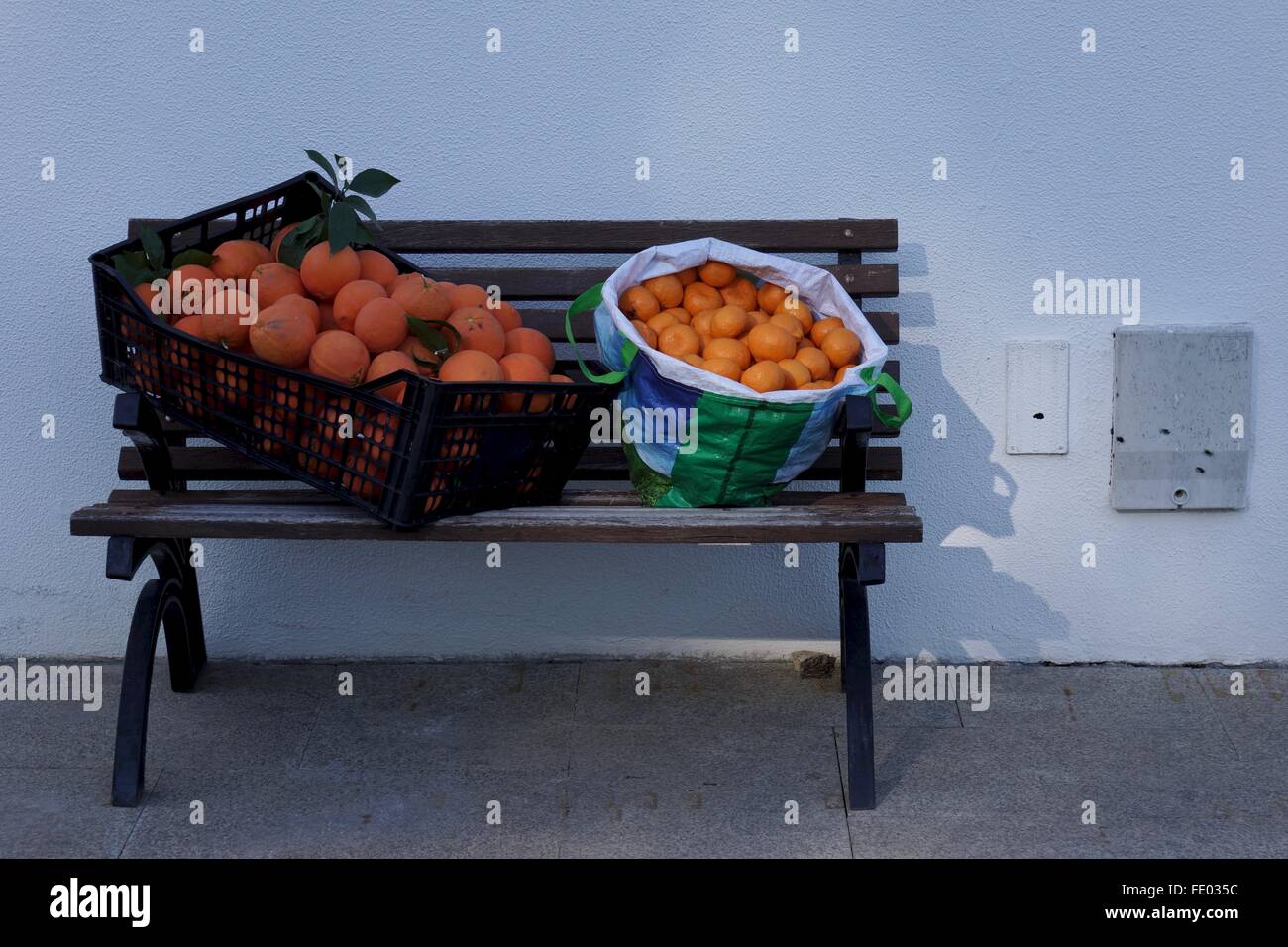 Eine Kiste und Beutel mit frisch gepflückt Orangen auf einer Bank. Stockfoto
