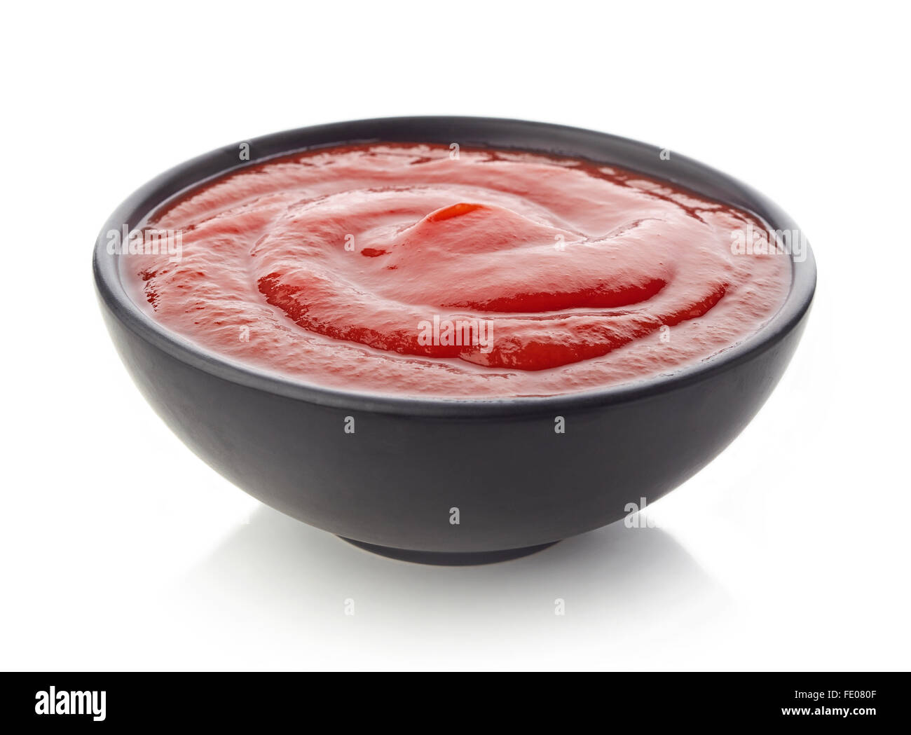 Schwarze Schale mit Ketchup oder Tomaten Sauce auf weißem Hintergrund Stockfoto