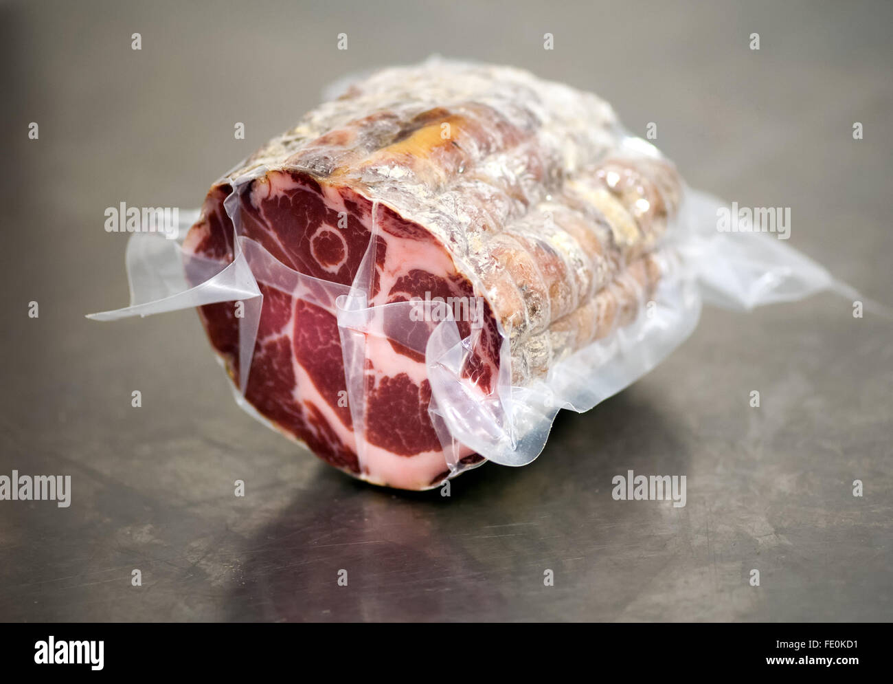 Rolle der Luft geheilt Schweinefleisch in Verpackung auf Metall-Tisch in Lebensmittel verarbeitenden Anlage bedeckt Stockfoto