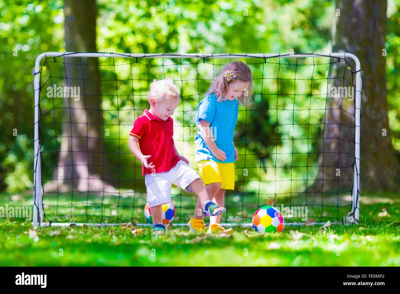 Zwei glückliche Kinder spielen Fußball im Freien im Schulhof. Kinder spielen Fußball. Aktiv Sport für Vorschulkind Stockfoto