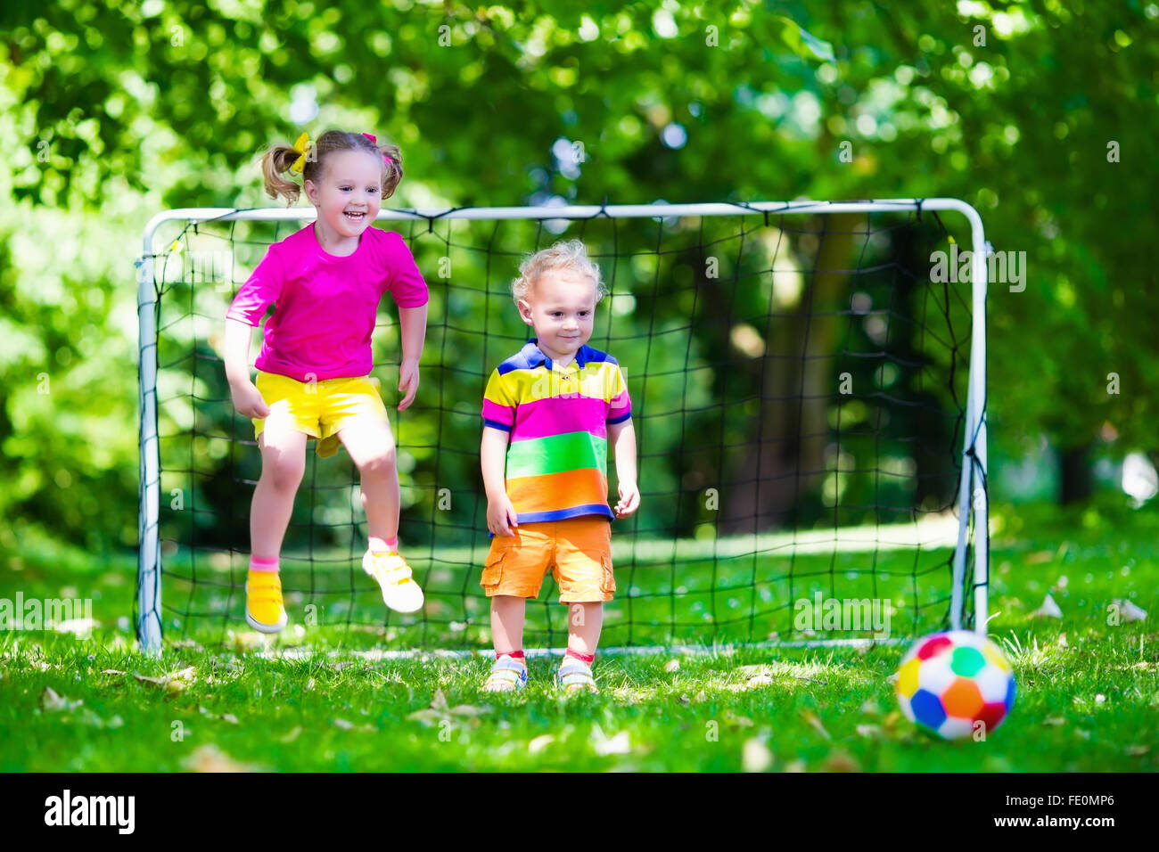 Zwei glückliche Kinder spielen Fußball im Freien im Schulhof. Kinder spielen Fußball. Aktiv Sport für Vorschulkind Stockfoto
